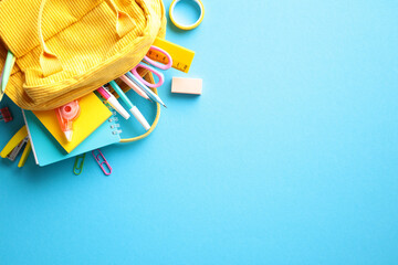Colorful Back to School Concept. Yellow backpack with various school supplies, including pencils,...