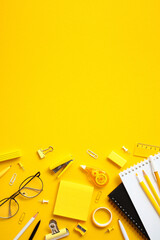 Vibrant yellow background with neatly organized office supplies including pencils, pens, notepad,...