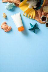 Summer Beach Essentials on Blue Background. A vibrant and playful arrangement of beach holiday items including sunscreen, children’s plastic toys in the shape of sea creatures, stylish sunglasses.