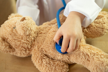 little child, blonde girl 4 years old plays with toy, little doctor treating teddy bear, happy childhood, vocational guidance, plush friend