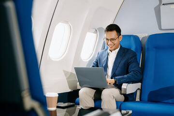 Asian executive excels in first class, multitasking with digital tablet, laptop and smartphone....