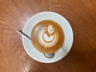hot brew drink cappuccino kopi coffee mocha piccolo latte expresso with milk in traditional cup and tea spoon and small plate on wood table vegan healthy restaurant beverage cafe halal food bar menu