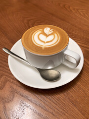 hot brew drink cappuccino kopi coffee mocha piccolo latte expresso with milk in traditional cup and tea spoon and small plate on wood table vegan healthy restaurant beverage cafe halal food bar menu