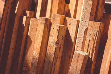 Group of the old wood timbers leaning against the wall inside of storage house with light and...