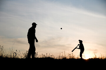 A Happy child with parent playing baseball concept in park in nature