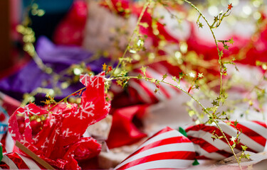A vibrant and festive close-up of Christmas wrapping paper and decorations featuring red and white stripes, snowflake patterns, and golden star garlands.