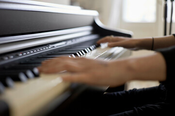 A person is playing a piano, focusing on their hands moving across the black and white keys.