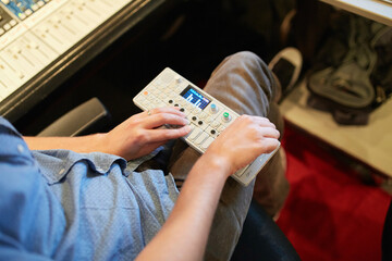 A person is operating an audio mixer, focusing on adjusting the settings with their hands.