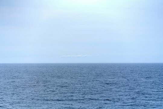 This image displays a serene view of the open ocean under a calm, overcast sky.