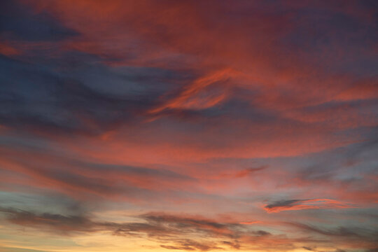 The image captures a vibrant sunset sky with a blend of orange, red, and blue hues, highlighting the dynamic and soft cloud formations.