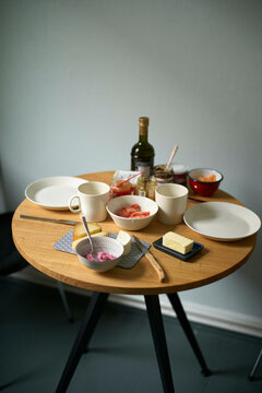 A well-arranged breakfast table with bowls, plates, cups, a bottle, and various food items, exhibiting a cozy and inviting atmosphere.