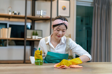 The young woman is wiping/cleaning the table