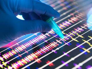 Genomic Research, Scientist holding a DNA sample in a vial with the profile results on screen in the lab