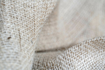 This is a close-up image of burlap fabric showcasing its coarse texture and woven pattern with focus on the overlapping layers.
