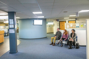 Three people waiting in a modern reception area of a medical practice