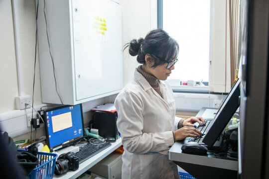 Scientist working at computer in lab of a medical practice, UK