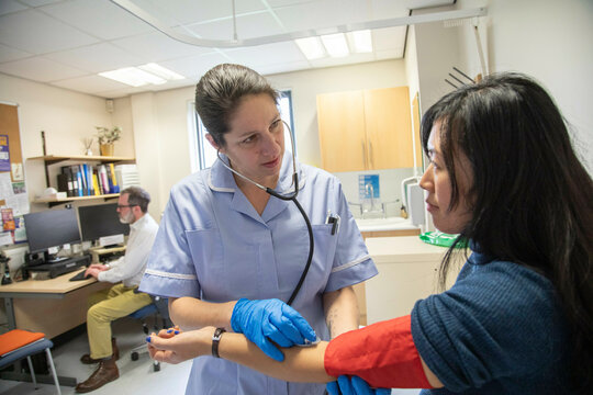 Nurse examining a patient's arm for blood pressure and pulse