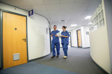Two healthcare professionals walking in a hospital corridor, medical practice UK