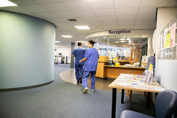 Two healthcare professionals walking towards a reception area of a medical practice