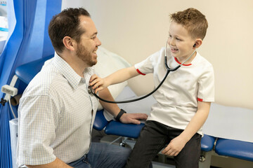 Boy using stethoscope on doctor for fun