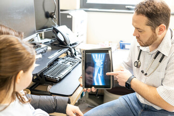 Doctor showing X-ray to a child on a tablet