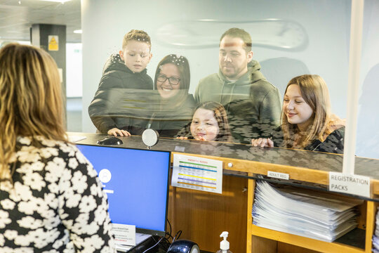 Family at a reception desk of a medical practice for registration