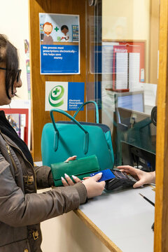 Woman making a contactless payment at a reception desk of a medical practice