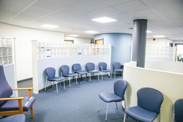 Empty waiting room with blue chairs and wall-mounted bulletin boards of a medical practice