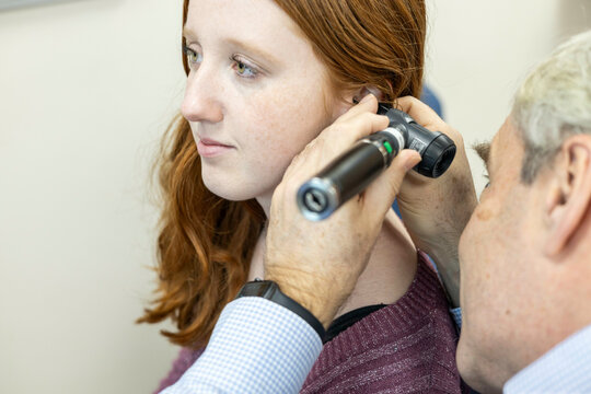 Doctor examining patient's ear with an otoscope