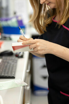 Pharmacist writing on a medicine box in a pharmacy.