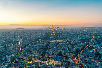 Aerial view of Paris with the Eiffel Tower illuminated at dusk.