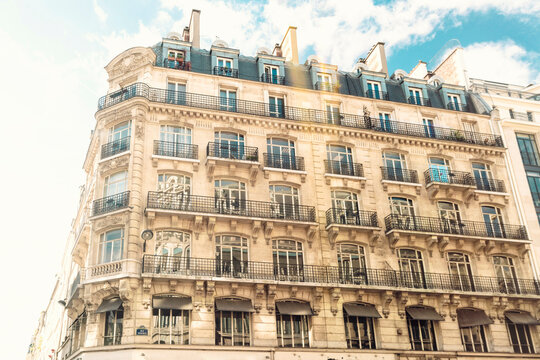 Elegant European building with balconies and attics under a blue sky.