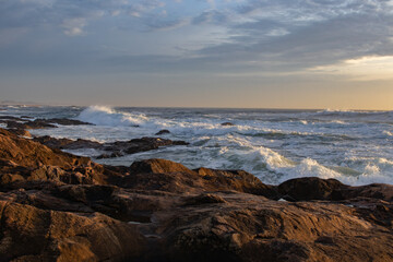 small waves breaking in the ocean next to rocks and waves