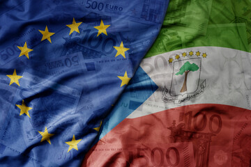 big waving realistic national colorful flag of european union and national flag of equatorial guinea on a euro money banknotes background.