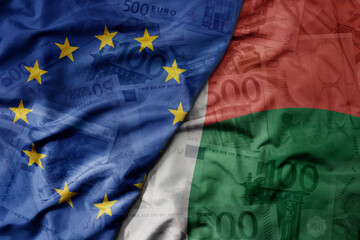 big waving realistic national colorful flag of european union and national flag of madagascar on a euro money banknotes background.