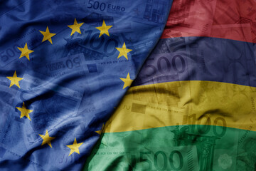 big waving realistic national colorful flag of european union and national flag of mauritius on a euro money banknotes background.