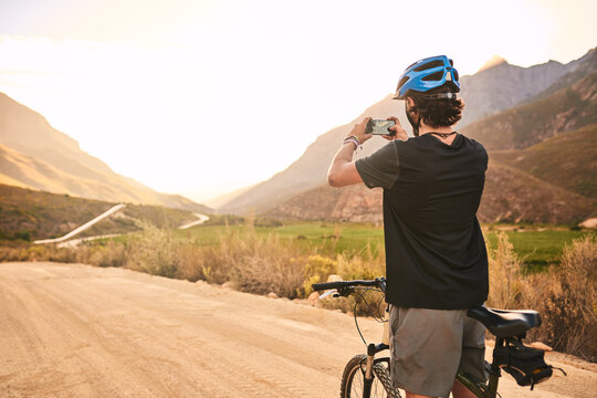 Phone, photography and man with bicycle on mountain for outdoor journey, exercise and memory in morning. Bike, relax and male person with picture in nature for workout, update or cycling in Australia