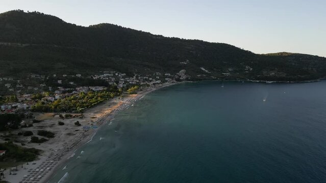 Golden beach at sunset with clear waters of the aegean and boat passing underneath