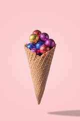 Ice cream cone with colored candyes on pink background. Minimal