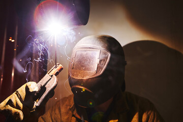 Male in face mask welds with welding