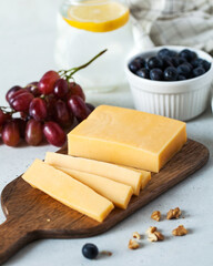 Cheese slices with grapes on a wooden plate