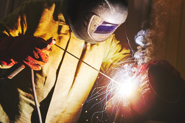 Male in face mask welds with welding