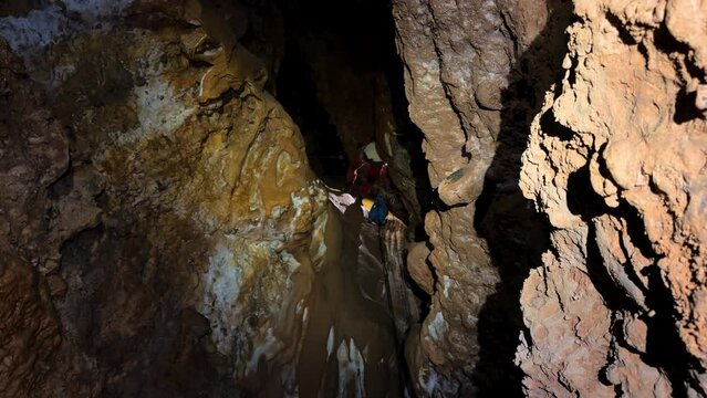 An unrecognizable adventurous man rappelling down a rock with ropes while spelunking in an exciting cave. High quality 4k footage