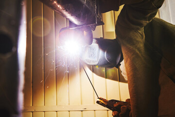 Worker in safety mask welds metal at industrial enterprises.