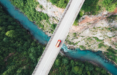 High angle view of car carrying canoe crosses the bridge over a canyon, a turquoise mountain river...