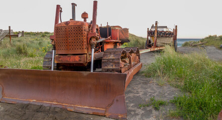 Old bulldozer and boat on trailer on beach