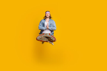 Full body portrait of cool young man jump fly meditate wear denim shirt isolated on yellow color...