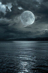 a serene night landscape with a luminous full moon above a still body of water and clouds