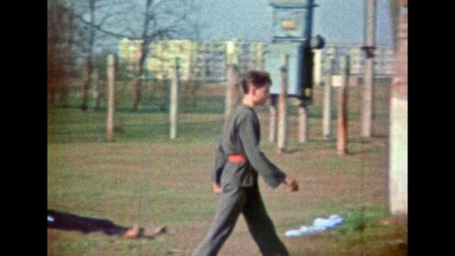 Funny scene with confident young man walking through defeated enemies. Winner hand combat fighter. Humor exaggerating strength. Man power hyperbole on battlefield. Vintage film. Retro 1980s archive