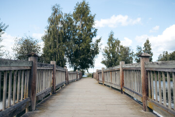 View from the center of beginning of a wooden bridge, end of bridge in the background with trees